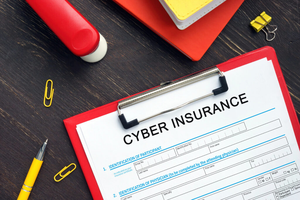 Cyber insurance application form on a clipboard with office supplies on a desk.