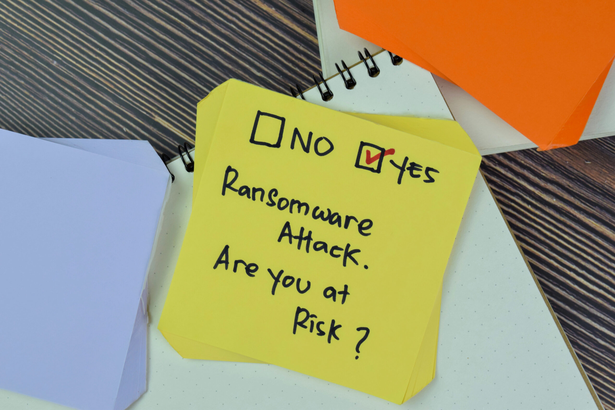 Sticky note asking about ransomware attack risk with yes checkbox marked for cybersecurity awareness.